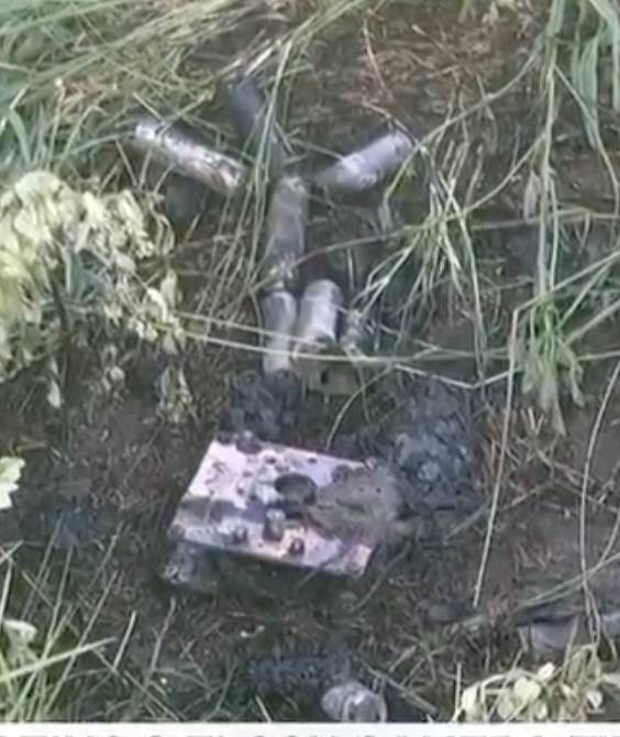 Cylindrical lithium cells and a scorched metal plate in the burned grass